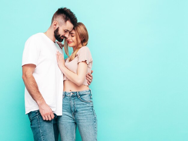 Sexy smiling beautiful woman and her handsome boyfriend Happy cheerful family having tender moments near blue wall in studioPure cheerful models huggingEmbracing each other Cheerful and happy