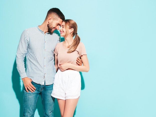 Sexy smiling beautiful woman and her handsome boyfriend Happy cheerful family having tender moments near blue wall in studioPure cheerful models huggingEmbracing each other