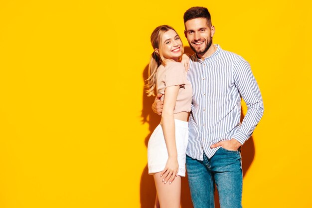 섹시하게 웃고 있는 아름다운 여성과 그녀의 잘생긴 남자친구 스튜디오의 노란 벽 근처에서 부드러운 순간을 보내는 행복한 쾌활한 가족순수한 쾌활한 모델 포옹 서로 포옹