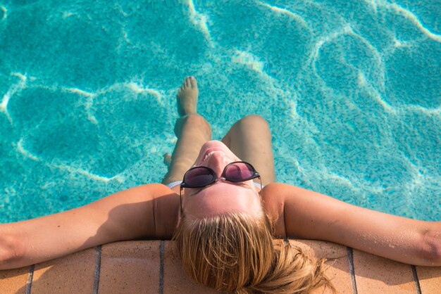 Sexy woman in bikini enjoying summer sun and tanning during holidays in pool. Top view. Woman in swimming pool. Sexy woman in bikini.