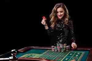 Free photo sexy woman in a black dress playing in casino. woman stakes piles of chips playing roulette at the casino club. gambling. roulette.