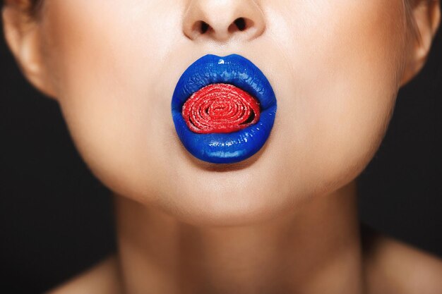Sexy woman's colorful lips holding sweeties