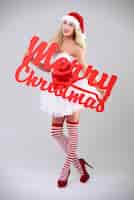 Free photo sexy woman in santa costume on grey wall