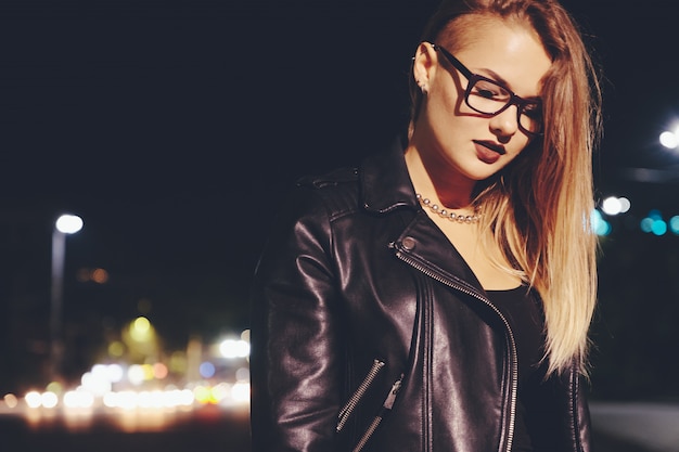 Sexy woman with long hair in leather clothes on night city street