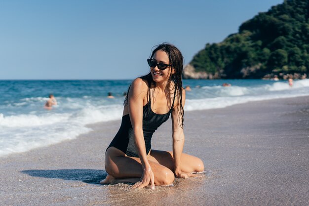 海で彼女の膝の上でポーズセクシーな若いブルネット