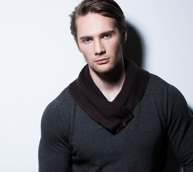 Sexy young man in casual poses over wall with contrast shadows 