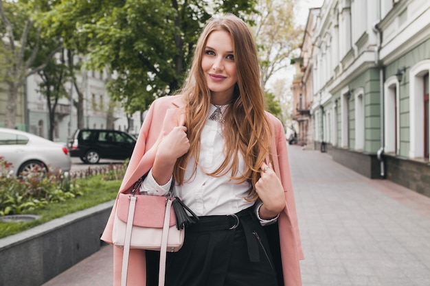 Сексуальная молодая стильная красивая женщина гуляет по улице в розовом пальто