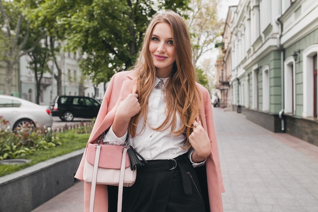 Sexy young stylish beautiful woman walking in street, wearing pink coat