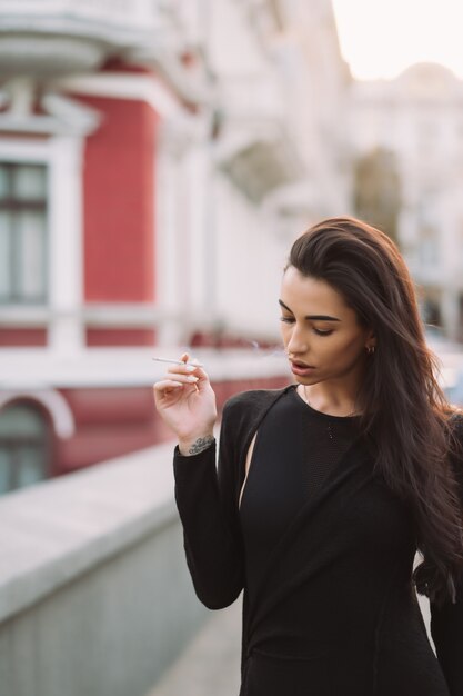 Sexy, young woman in the body smokes in the street