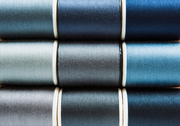 Free photo shades of gray and blue sewing threads background closeup