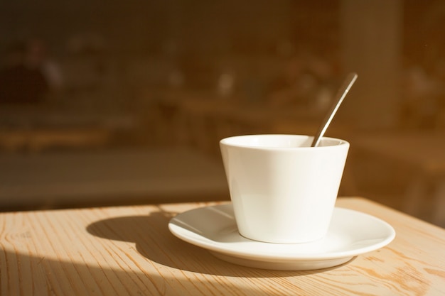 コーヒーカップとソーサーの木製の机の上の影