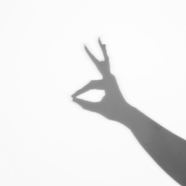 Тень с человеческим пальцем и руками на белом фоне