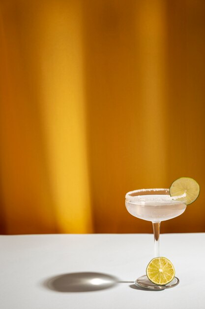 Shadow of margarita cocktail glass with salty rim on white table