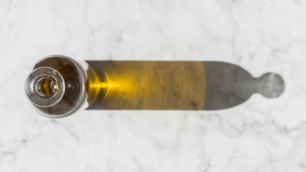 Shadow of oil bottle on white marble background