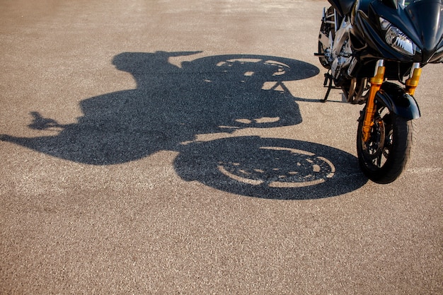 Shadow of orange motorbike on asphalt
