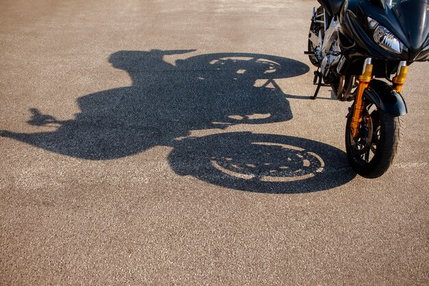아스팔트에 주황색 오토바이의 그림자
