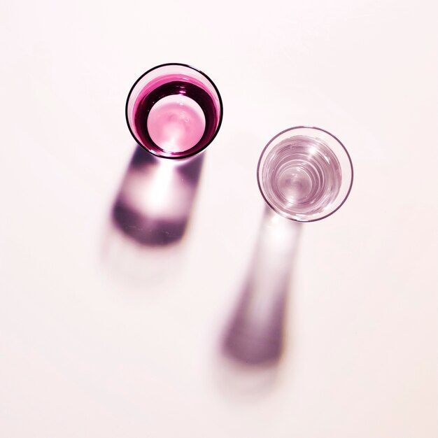 Free photo shadow of two water glasses on plain background