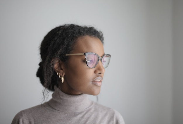 Shallow focus of an African-American female with glasses wearing a gray turtleneck