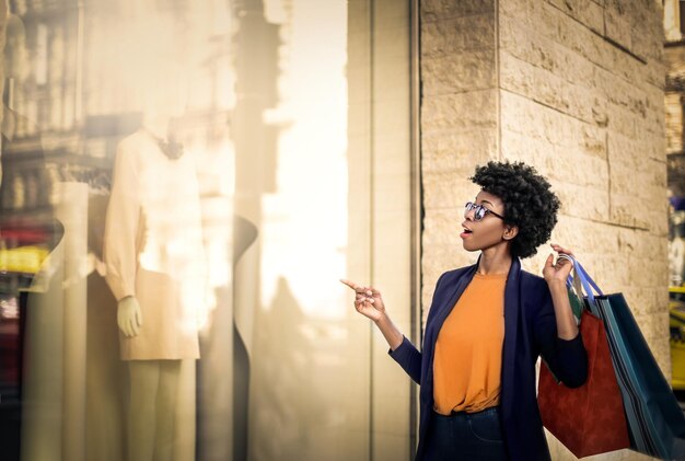 Shallow focus of an excited African woman with bags shopping outdoors under the sunlight