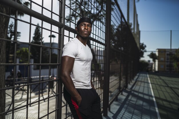 Shallow focus shot of an African-American male in a white shirt leaning on a fence