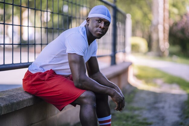 Shallow focus shot of an African-American male in a white shirt sitting on a concrete surface