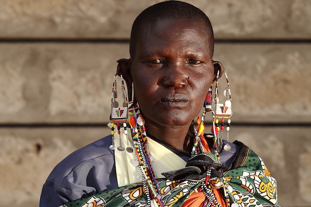 Foto gratuita colpo poco profondo del fuoco di un maschio africano con i grandi orecchini mentre esamina la macchina fotografica