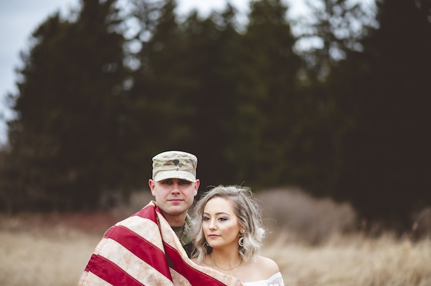 Shallow focus shot of an American soldier with his wife wrapped in an American flag