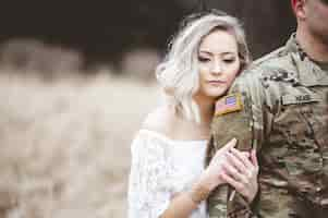 Free photo shallow focus shot of an attractive female holding an american soldier's arm