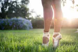 Free photo shallow focus shot of the feet of a ballet dancer standing on the green grass