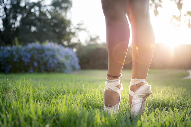 Shallow focus shot of the feet of a ballet dancer standing on the green grass