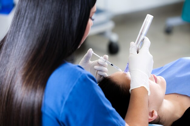 A shallow focus shot of a female doctor performing Botox