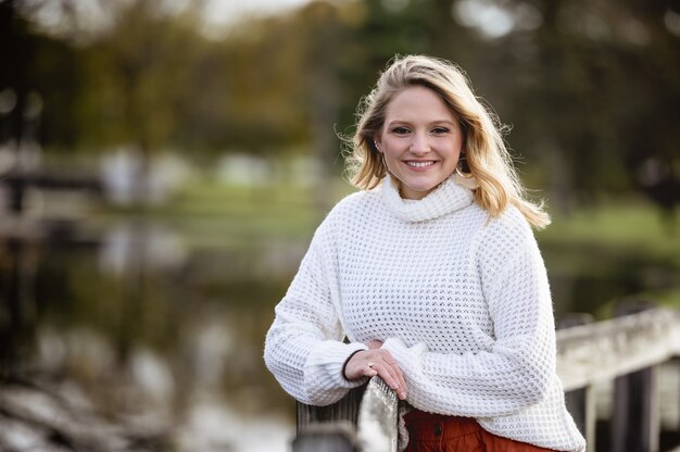 Shallow focus shot of a female leaning against a wooden fence and smiling at the camera