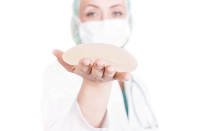 Shallow focus shot of a female plastic surgeon holding a breast implant
