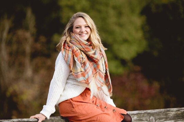 Shallow focus shot of a female sitting on a wooden and smiling at the camera