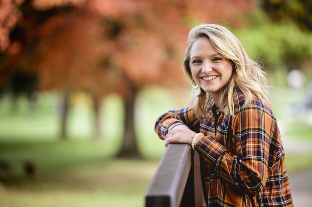 Shallow focus shot of a female with her hands on the fence while smiling at the camera