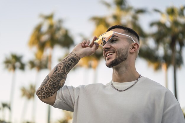 Shallow focus shot of a handsome Spanish Caucasian man with tattoos and sunglasses posing outdoors