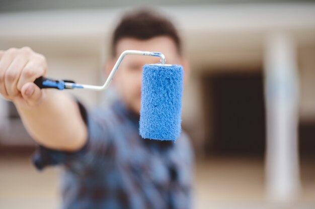 Shallow focus shot of a male holding a blue colored brush