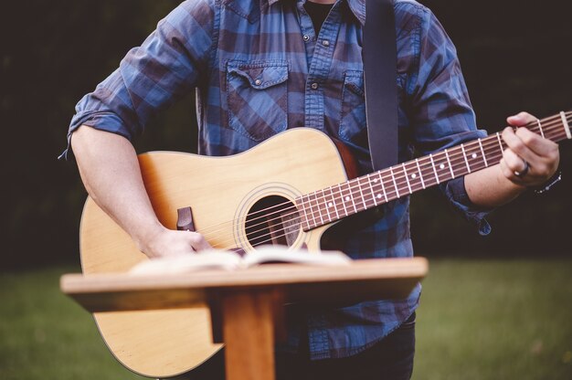 Shallow focus shot of a male playing guitar near a speech stand
