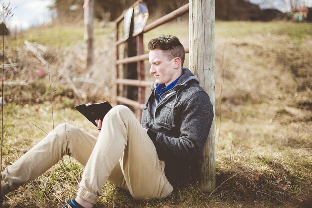 성경을 읽는 동안 바닥에 앉아있는 남성의 얕은 초점 샷
