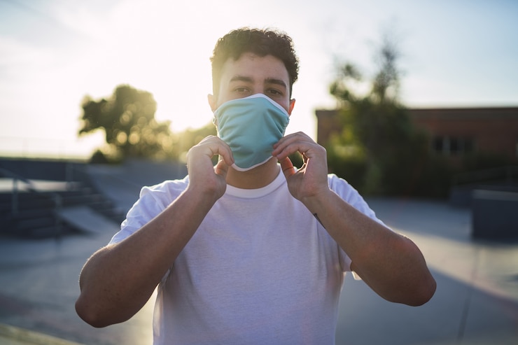 Free Photo shallow focus shot of a male in a white shirt wearing a face mask at the park- covid-19 concept