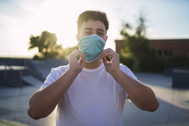 Shallow focus shot of a male in a white shirt wearing a face mask at the park- Covid-19 concept