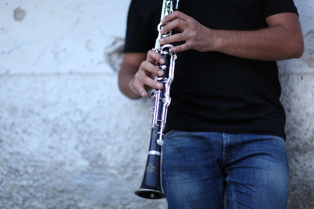 Shallow focus shot of a person playing clarinet in front of a white wall