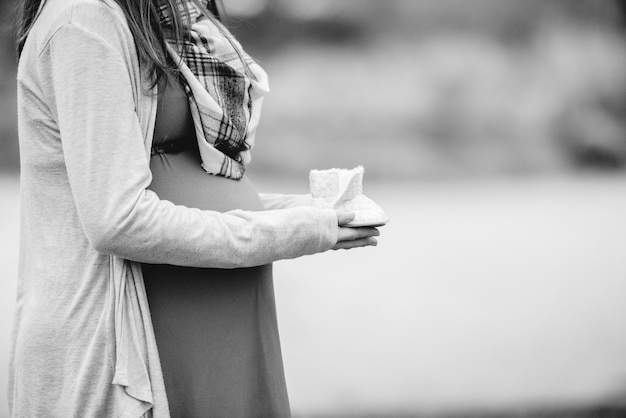 A shallow focus shot of a pregnant woman holding a newborn shoes