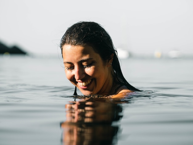 Shallow focus shot of a smiling female swimming in the sea