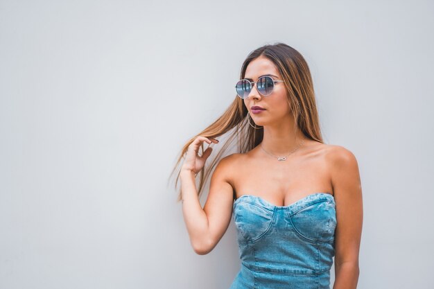 Shallow focus shot of a young caucasian woman wearing a denim dress and sunglasses