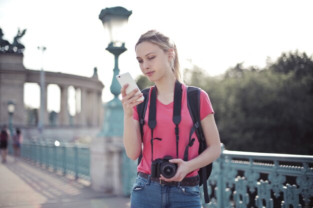 Shallow focus shot of a young female doing a city tour and holding in hands a smartphone