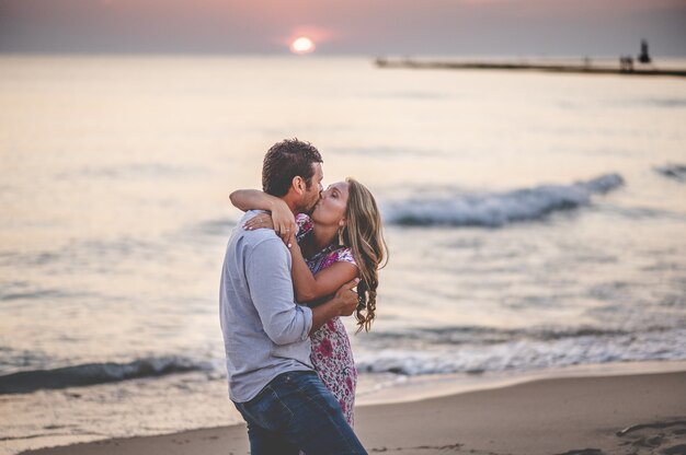 ビーチでキスしている若い素敵なカップルの浅いフォーカスショット