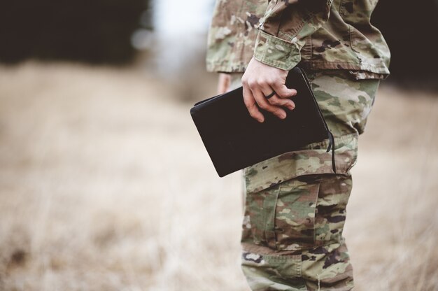 フィールドで聖書を持っている若い兵士の浅いフォーカスショット