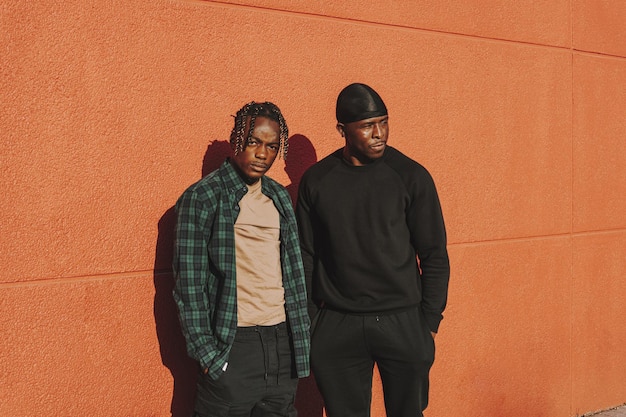 Free photo shallow focus of two black men standing against a red wall