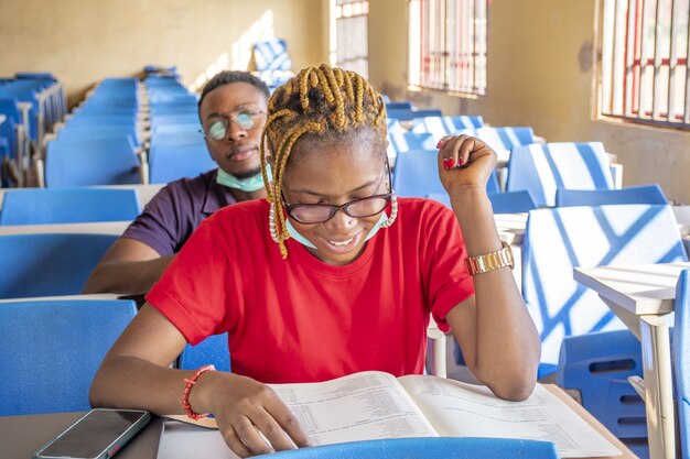 Shallow focus of two students wearing facemasks and studying in a classroom